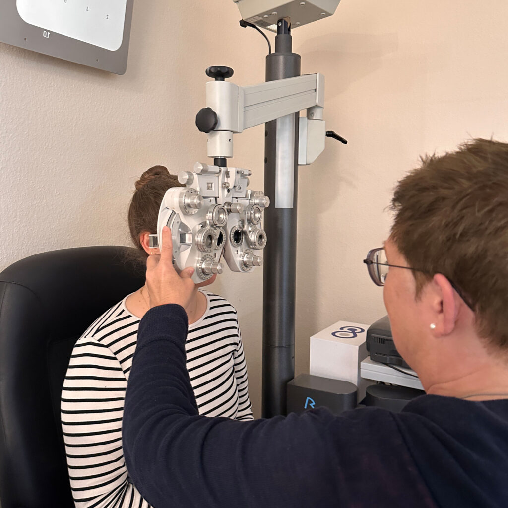Eine Frau mit Brille führt bei einer Patientin einen Sehtest durch.